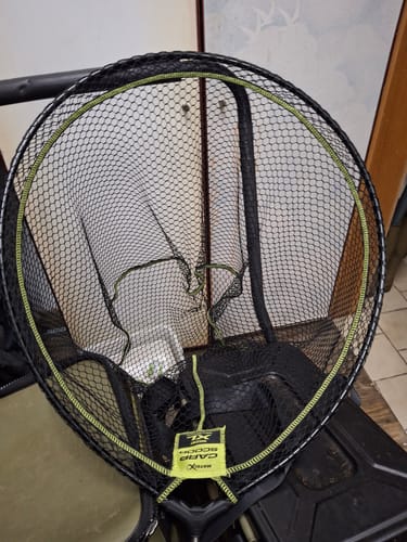 Beoordelaar toont het CARP SCOOP LANDING NET schepnet, maat XL, met een zwart gaas en een groene rand.