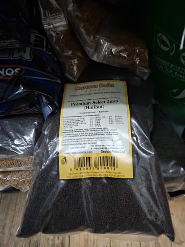 Recensent toont een grote, doorzichtige zak met Premium Select (Black Halibut) pellets.