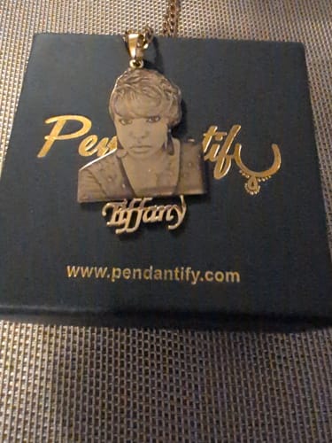 Customer's gold-colored custom photo engraved pendant necklace with the name 'Tiffany', resting on its gift box.
