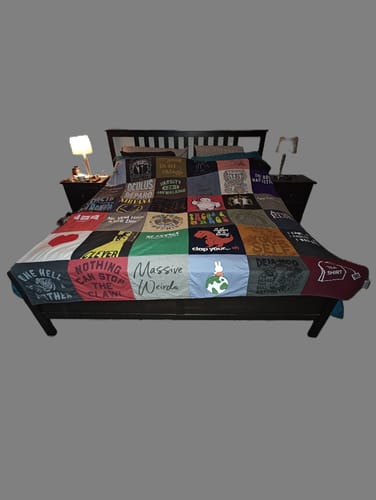 Customer's large Premium T Shirt Quilt, made of colorful t-shirts, spread across a king-sized bed.