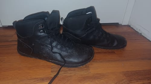 Asiakkaan mustat Vaistoa Uoma 2 -paljasjalkavaelluskengät puulattialla.