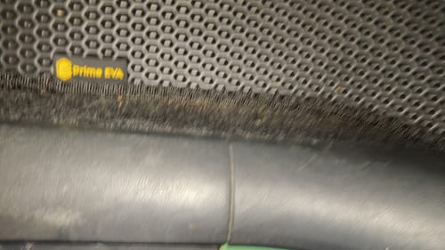 Zbliżenie na czarny dywanik samochodowy klienta z widocznym logo Prime EVA i fakturą plastra miodu.