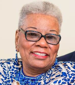 A close-up photo of a smiling reviewer with short hair and glasses who uses the Emma product.