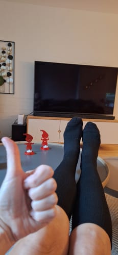 Anmelder slapper af med fødderne oppe iført sorte støttestrømper og giver en tommel op.