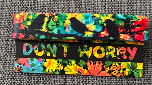 Reviewer's close-up of the colorful Don't Worry Bracelet on its packaging, showing the bird silhouettes.