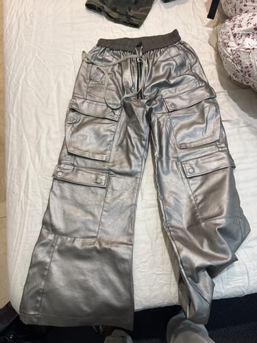 Reviewer's metallic baggy trousers with cargo pockets laid flat on a bed.