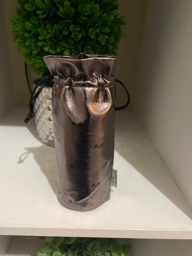 Customer's Cedrat Boise Intense perfume shown in its shiny bronze pouch on a shelf.