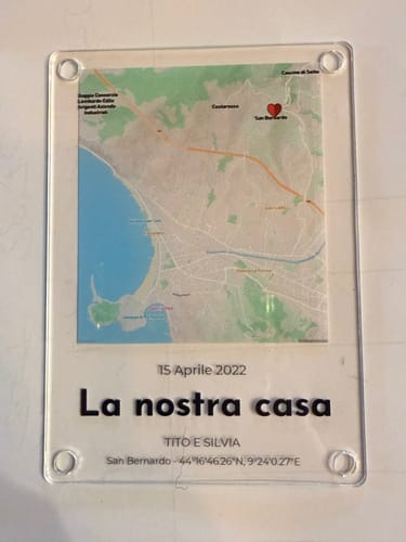 Kunde zeigt einen personalisierten Acrylmagneten mit einer Karte, einem Datum und der Aufschrift „La nostra casa“.