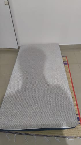 Customer's Flo Anti-Gravity™ Latex Mattress with its grey textured cover, placed on a mat on the floor.
