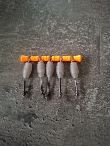 Recensent toont vijf oranje Guru Pole Elastic Connectors op een rij op een donkere ondergrond.