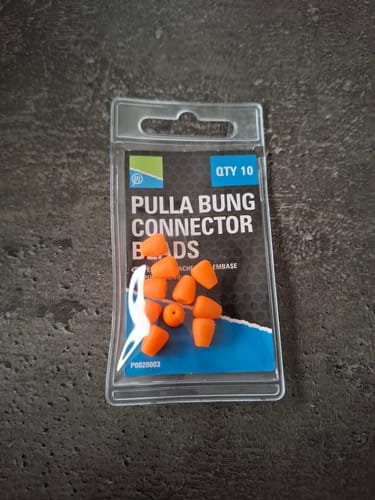 Beoordelaar toont de oranje Pulla Bung Connector Beads in de originele doorzichtige verpakking.