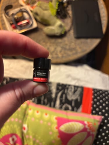 Close-up of a customer holding a small vial of Petals And Petrichor scent.
