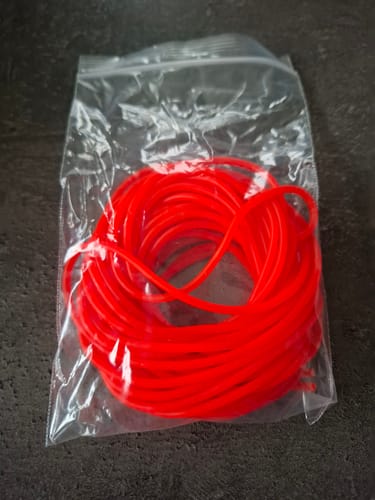 Recensent toont de felrode Slik Elastic in de plastic verpakking.