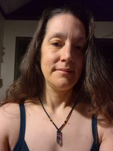 Reviewer wearing the Natural Fluorite Necklace with a purple crystal pendant on a black string.