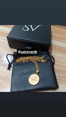 El colgante Compass Pendant Oro de un cliente sobre su estuche y caja negros.
