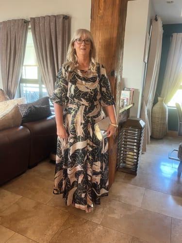 Kunde som poserer i den elegante, mønstrede maxikjolen med trekvart ermer.