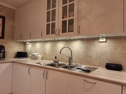 Kunde viser Premium Limewash beige kontaktplast brukt som backsplash i et kjøkkenhjørne over vasken.