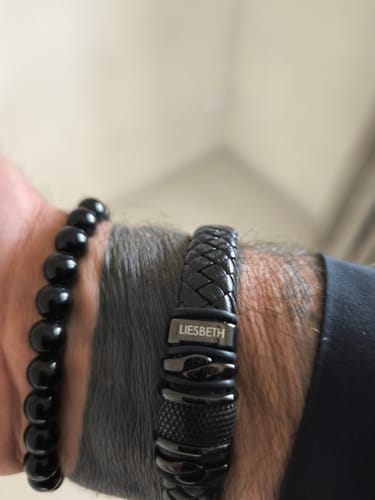 Customer wearing the personalized black bracelet on their wrist, showing the name 'LIESBETH' engraved on the clasp.