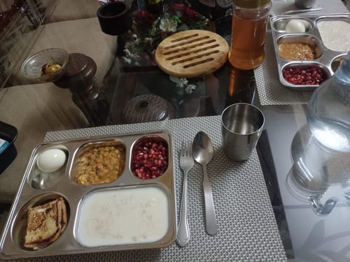 Customer's Korean Style Lunch Tray with a portioned meal set on a dining table with a steel cup and cutlery.