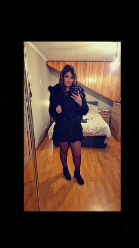 Reviewer taking a mirror selfie while wearing the Black Faux Fur Lapel Short Jacket as part of an all-black outfit in a bedroom.