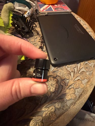 Reviewer holding a small black sample vial of the Khal Drogo perfume.
