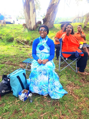 Reviewer sitting outdoors in the floral maxi dress, which they've styled over a long-sleeved blue top.