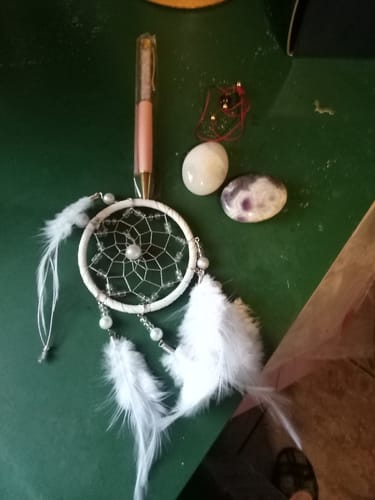 Customer's items from the AuraBloom Subscription Box, including a dream catcher, a crystal pen, and two polished stones.