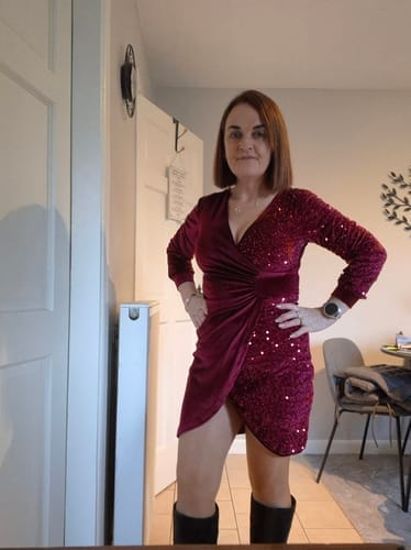 Anmelder i en glitrende, burgunderrød kjole med v-hals og paljetter, fotografert innendørs.