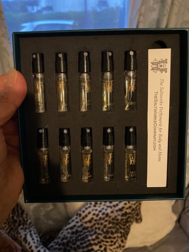Customer holding the open Discovery Set, showing ten perfume sample vials neatly arranged in the box.