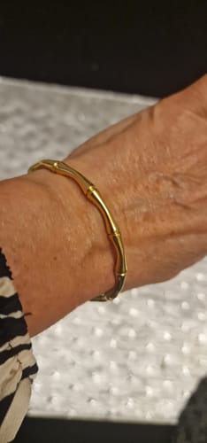 Close-up of a reviewer's wrist wearing a gold-colored, bamboo-style bangle.