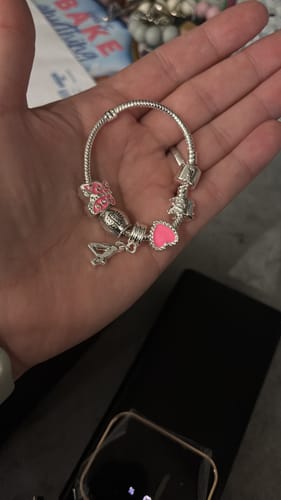 Customer holding the silver-plated children's charm bracelet, showing the pink heart and butterfly charms.