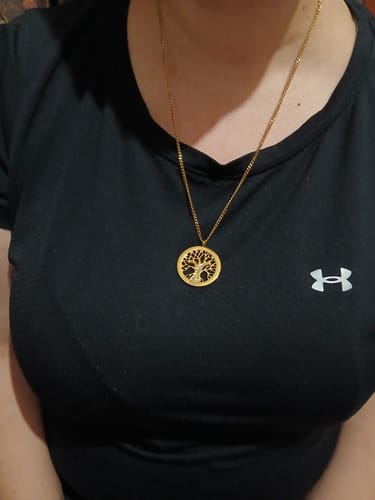 Customer wearing the gold Tree of Life necklace against a black shirt.
