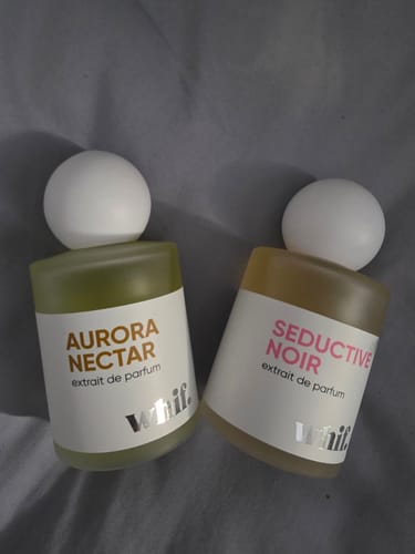 Customer's two Whif perfume bottles, Aurora Nectar and Seductive Noir, on a grey fabric background.