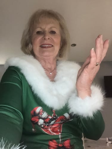 Kunde i den grønne juletoppen med hvit pelskant og nissetrykk.