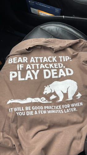 Customer's brown Bear Attack Tip T-shirt laid out, showing the humorous graphic and text on the back.