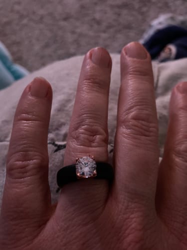 Close-up of a reviewer's hand wearing the Silicone Ring, showing the black band and sparkling solitaire CZ stone.