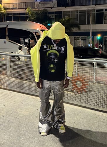 Customer wearing the silver, multi-pocket matte coated overalls as part of a streetwear outfit at night.