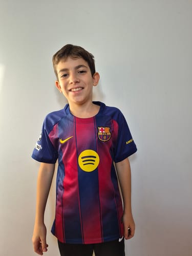 Un cliente mostra un ragazzo sorridente che indossa la MAGLIA BARCELLONA HOME.