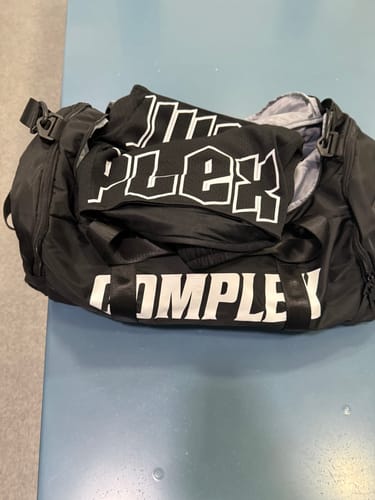Customer's black Complex Lightning Shorts with a white logo, seen resting inside a black gym bag.