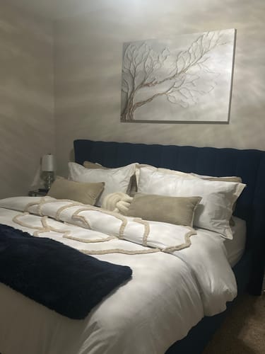 Customer's textured Tree Canopy Wall Art in neutral tones hanging above a bed with a dark blue headboard.