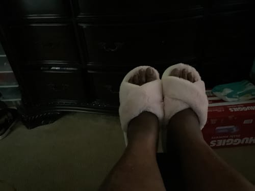 Customer wearing a pair of soft, light pink The Cloudies™ slippers with a criss-cross design.