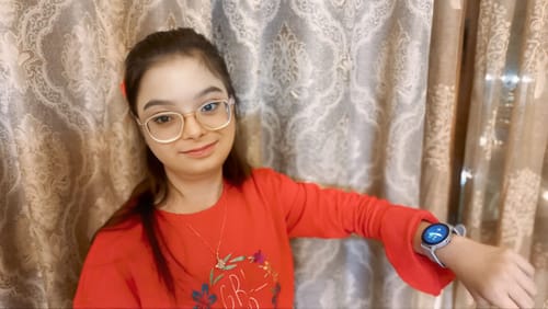 Close-up of a reviewer wearing the Valentina Smartwatch with a glowing blue screen on their wrist.