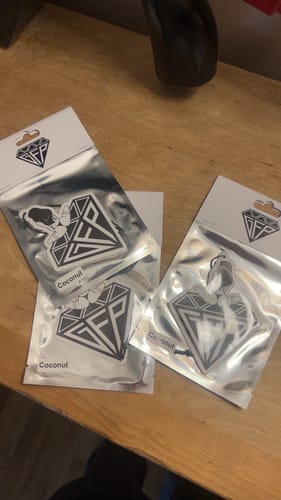 Customer's three LIMITED EDITION AIR FRESHENER packs in their shiny packaging on a wooden table.