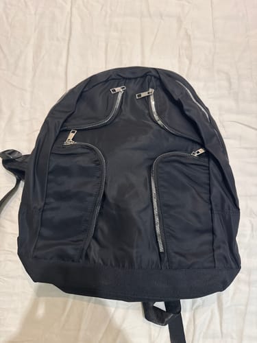 Customer's black Multi-Pocket Nylon Backpack laid flat on a white surface, showing its multiple zippered pockets.