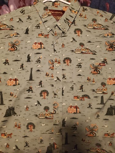 Customer's 'Frodo's Journey' short sleeve shirt laid out, showing the detailed storybook-style pattern on the grey fabric.