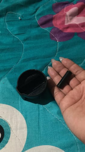 La mano de un cliente sostiene las dos piezas de una perilla rota de la estufa Acros.