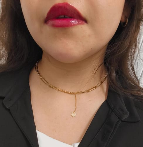 Primer plano de una clienta usando el Collar Luisa dorado, que combina dos estilos de cadena y un dije.