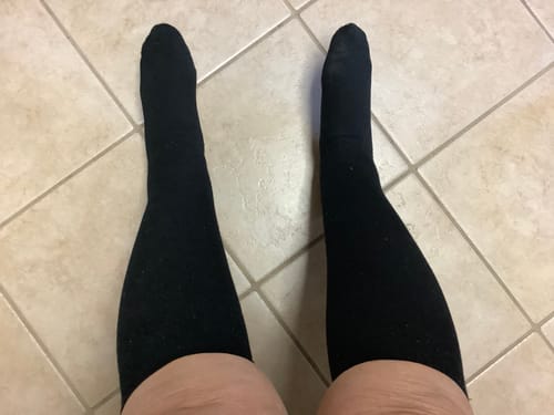 Customer's point-of-view shot wearing the black Performance Eucalyptus Compression Socks on a tiled floor.