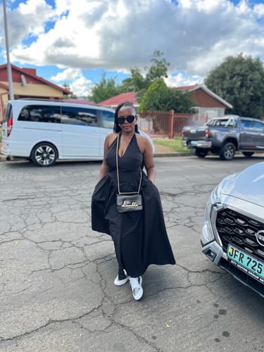 Reviewer wearing the black Halter Backless Pleated A-Line Maxi Dress outdoors with white sneakers.