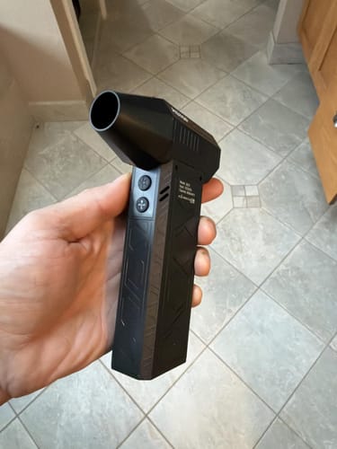 Customer holding the black, compact Litlamp™ Turbo LED Blower in their hand, showing its size and buttons.